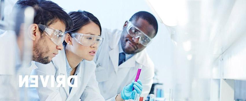 图片上是三个人在实验室工作，戴着安全眼镜，穿着白大褂，